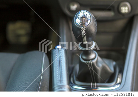 Luxurious car black leather interior. Close-up detail of handbrake manual brake and gearshift stick on blurred dashboard background. Transportation, design, modern technology concept. Luxurious car black leather interior. Close-up detail of handbrake manual brake and gearshift stick on blurred dashboard background. Transportation, design, modern technology concept. 132551812