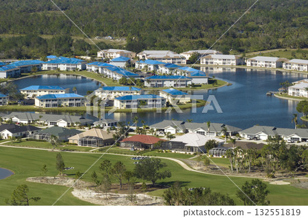 Leaking roofs of residential condos covered with protective tarp sheets against rain water leaks until replacement of shingles. Damage of building rooftops as aftermath of hurricane in Florida. Leaking roofs of residential condos covered with protective tarp sheets against rain water leaks until replacement of shingles. Damage of building rooftops as aftermath of hurricane in Florida. 132551819