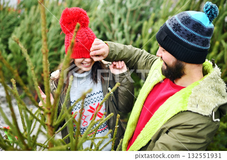 young couple man and woman have fun and fool around on the background of Christmas trees young couple man and woman have fun and fool around on the background of Christmas trees 132551931