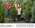 a young family - parents and two daughters are smiling against the backdrop of a Christmas tree shop. Preparing for Christmas. 132551936