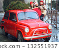 family - mother, daughter and father in Santa's hat are hugging and smiling on the background of a red retro car with a Christmas tree on the roof. 132551937