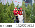 a young family - parents and two daughters are smiling against the backdrop of a Christmas tree shop. Preparing for Christmas. 132551938
