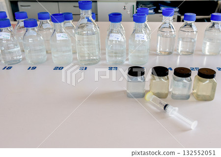 Laboratory storage bottles with blue polypropylene cap and plastic bottles on white table. 132552051