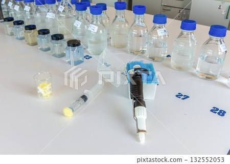 Laboratory storage bottles, plastic bottles, pipette, syringe and filters on white table. 132552053