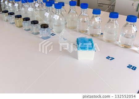 Laboratory storage bottles with blue polypropylene cap and plastic bottles on white table. 132552054