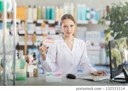 Female pharmacist standing at drugstore with medical product in hands 132553114