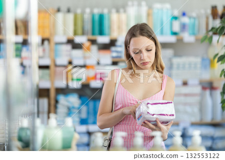 Young woman chooses feminine pads at pharmacy Young woman chooses feminine pads at pharmacy 132553122