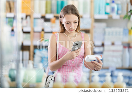 Girl in summer clothes scans code on package of pills to check expiration date Girl in summer clothes scans code on package of pills to check expiration date 132553271