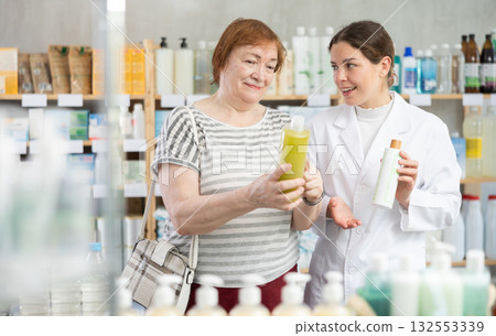 Woman holding shampoos in her hands next to pharmacist 132553339