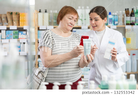 Woman buyer scans cream qr code with woman pharmacist 132553342