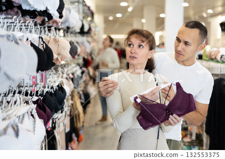 Young couple choosing nice brassiere in clothing store Young couple choosing nice brassiere in clothing store 132553375