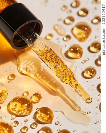 Golden serum in a glass dropper bottle with bubbles, water drops and bright reflections. Minimal luxury beauty concept 132553417