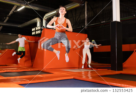 Cheerful woman jumping at modern colorful trampoline park 132553425