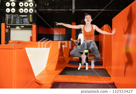 Middle-aged woman practice jumping on trampolines at trampoline center 132553427