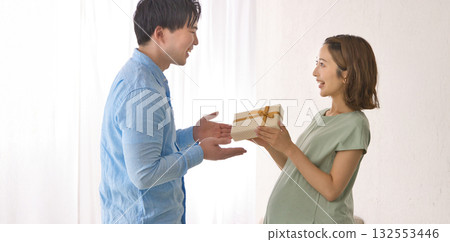 Young partner giving a gift to a pregnant woman Young partner giving a gift to a pregnant woman 132553446