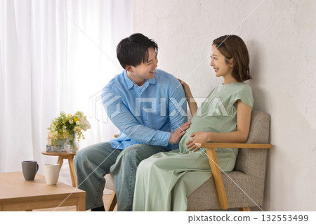 一對年輕夫婦在沙發上休息，孕婦 132553499