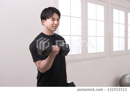 A man in his 20s doing muscle training with dumbbells A man in his 20s doing muscle training with dumbbells 132553513