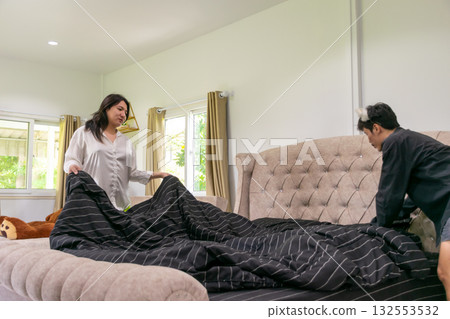 Two Thai LGBTQ friends making the bed together in the morning showing teamwork warmth and care representing friendship diversity and peaceful home lifestyle 132553532