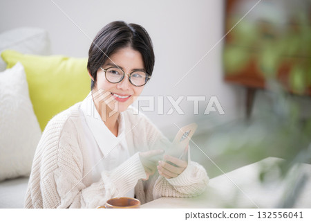 一位短髮女子戴著針織帽，正在敲擊她的智慧型手機 132556041