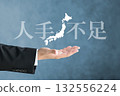 The hand of a person in a suit holding up a map of the Japanese archipelago and the words "Labor Shortage" 132556224