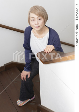 Senior woman with knee pain from going up and down stairs 132556403