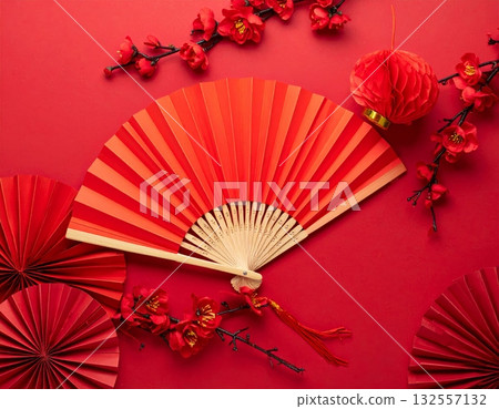 A traditional red Japanese folding fan opened with intricate paper patterns. 132557132