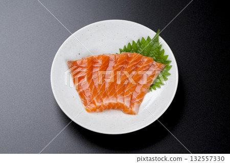 盛在盤子裡的鮭魚刺身，背景是黑色。 132557330