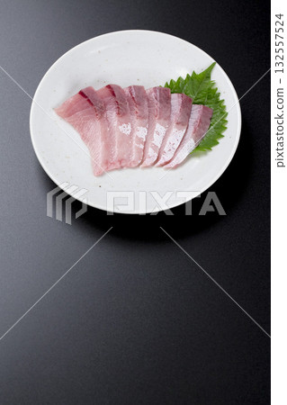 Yellowtail sashimi served on a plate against a black background 132557524