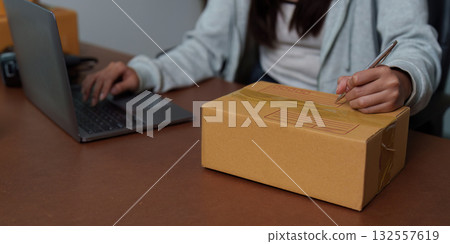 E-commerce: Individual labeling packages while using a laptop E-commerce: Individual labeling packages while using a laptop 132557619