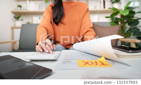 Tax preparation. Woman calculating taxes at home office with documents and calculator. 132557693