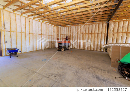 Unfinished interior features framing, insulation, construction lift in large space. 132558527