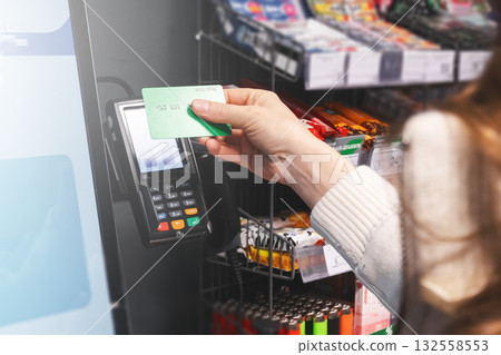 Payment by credit card at the self-service terminal with a touch screen in the store. A woman puts a credit card to the terminal close-up 132558553