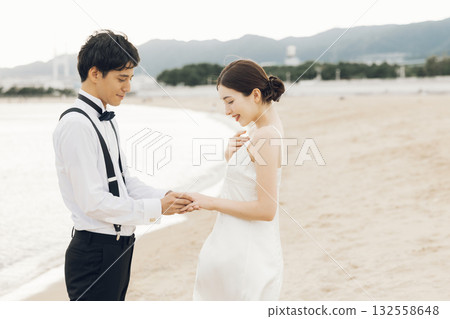 Man putting a ring on a woman's finger at the beach Man putting a ring on a woman's finger at the beach 132558648