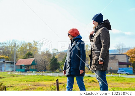 Two Russian women friends standing outdoors in Vladivostok, dressed warmly in jackets and hats, enjoying conversation on a cool autumn or spring day. Two Russian women friends standing outdoors in Vladivostok, dressed warmly in jackets and hats, enjoying conversation on a cool autumn or spring day. 132558762
