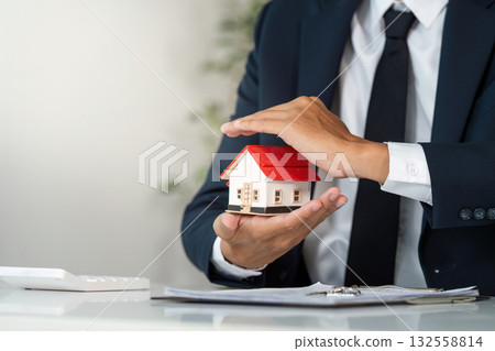 Real Estate Agent Protecting Home Model. Professional showcasing property value. Real Estate Agent Protecting Home Model. Professional showcasing property value. 132558814