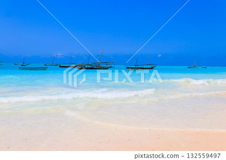 View of tropical sandy Nungwi beach and traditional wooden dhow boats in the Indian ocean on Zanzibar, Tanzania View of tropical sandy Nungwi beach and traditional wooden dhow boats in the Indian ocean on Zanzibar, Tanzania 132559497