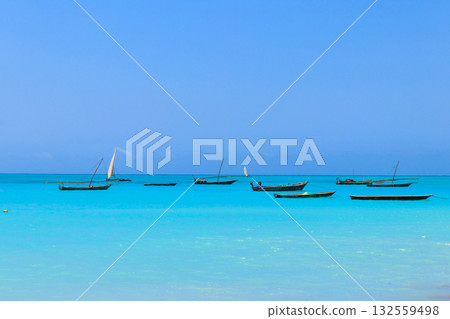 View of tropical sandy Nungwi beach and traditional wooden dhow boats in the Indian ocean on Zanzibar, Tanzania View of tropical sandy Nungwi beach and traditional wooden dhow boats in the Indian ocean on Zanzibar, Tanzania 132559498