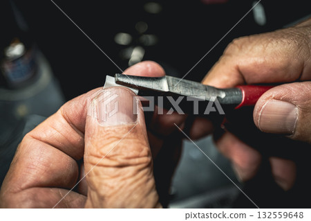 Man's hands bending plastic sheet with pliers 132559648