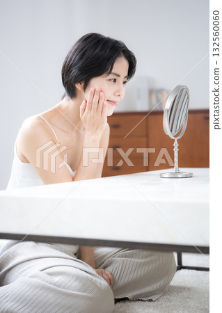 A beautiful woman with short black hair checking her skin care in the mirror. Image of beauty, beauty, and beautiful skin. 132560060