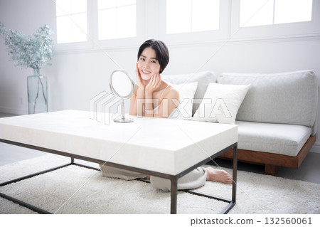 A beautiful woman with short black hair checking her skin care in the mirror. Image of beauty, beauty, and beautiful skin. 132560061