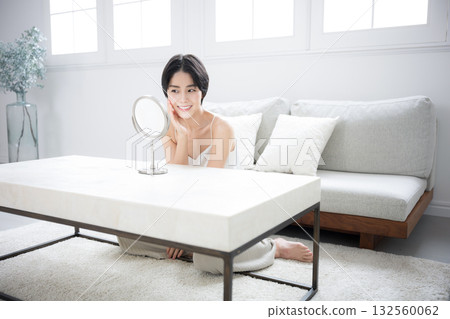 A beautiful woman with short black hair checking her skin care in the mirror. Image of beauty, beauty, and beautiful skin. 132560062