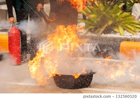 Firefighters use Fire extinguisher spraying chemical liquid fog gas to flame fire extinguishing 132560320