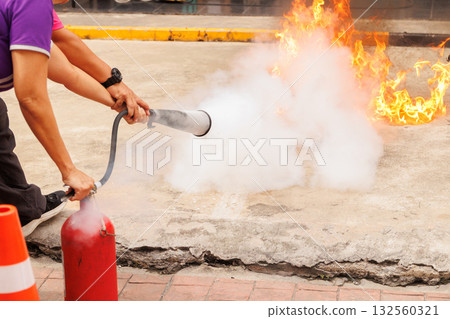 Firefighters use Fire extinguisher spraying chemical liquid fog gas to flame fire extinguishing 132560321