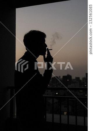 Silhouette of a man having a smoke on the balcony Silhouette of a man having a smoke on the balcony 132561085