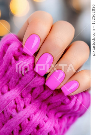 Elegant hand with neon pink manicure showcasing trendy style against soft knit background in natural lighting 132562056
