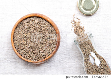 Aniseed, anise seeds, in a wooden bowl, on linen. Mistakenly called seeds, anise fruits, from the plant Pimpinella anisum are used to flavor food, candy, and alcoholic drinks around the Mediterranean. 132563416
