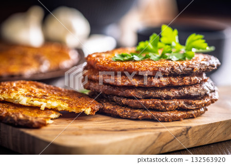 Fried potato pancake on cutting board on wooden table. Fried potato pancake on cutting board on wooden table. 132563920