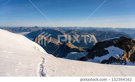 Climbers ascend the snowy slopes of Piz Palu in the Bernina Range, surrounded by stunning alpine views. Summer offers a perfect hiking experience across the glacier landscape. 132564162