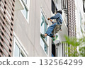 Exterior repair worker rappel down using ropes to repair leaking cement walls residential buildings. 132564299
