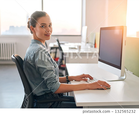 Professional woman working at computer in modern open office 132565232